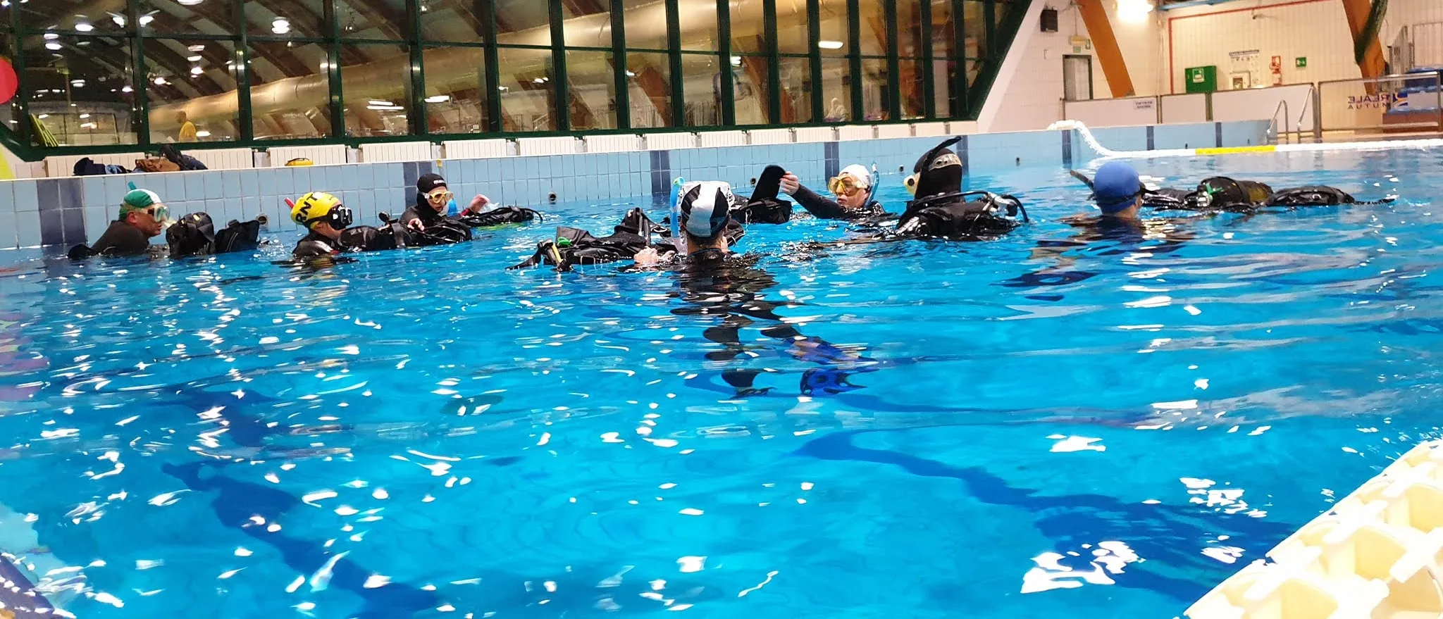 La classe del corso in acqua, allineata a bordo vasca durante la lezione